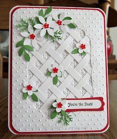 a white card with red and green flowers on it, sitting on top of a table