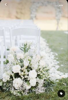 a bouquet of white flowers sitting on top of a grass covered field next to chairs