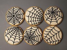 four decorated cookies sitting on top of each other with black spider webs in the middle