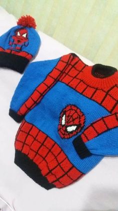 a spiderman sweater and hat are laying on a bed