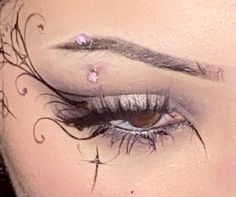 a woman's eye with some piercings on her forehead and lashes in front of her face