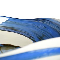 a blue and white wave shaped bowl with clouds in the background