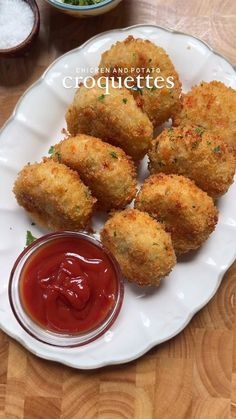 some fried food on a white plate with ketchup and dipping sauce in the middle