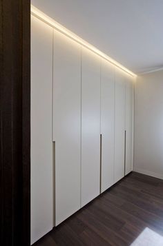 an empty room with white cupboards and wood flooring on the walls, along with wooden floors