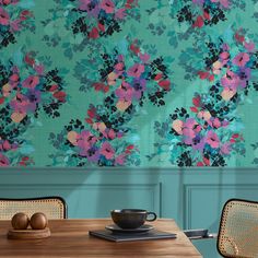 a teal floral wallpaper with pink and blue flowers on the walls in a dining room