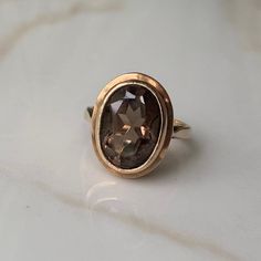 A vintage 9 carat gold ring, displaying a lovely cut smokey quartz.  CONDITION: Wear consistent with age and use. Stone in lovely condition. Please see photos for more detail. HALLMARKED 9 CARAT GOLD, ASSAYED IN BIRMINGHAM 1975 BAND WIDTH: 2mm SETTING HEIGHT: 6mm STONE FACE: 13mm X 9mm RING SIZE: UK: K 1/2 | US: 5 1/2 WEIGHT: 4.4 grams (UUZ) 1975 Band, 9mm Ring, Smokey Quartz Ring, Smoky Quartz Ring, Solitaire Rings, Quartz Ring, Smokey Quartz, Smoky Quartz, Solitaire Ring