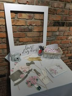 a white table topped with pictures and greeting cards next to a brick wall behind it