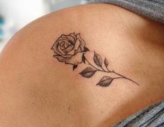 a rose tattoo on the back of a woman's left side ribcage