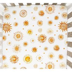 an orange and white crib sheet with sun designs on it