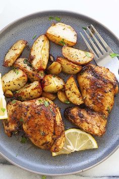 a plate with chicken, potatoes and lemon wedges