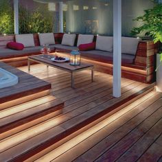 an outdoor deck with lights on the side and couches, coffee table and hot tub