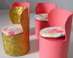 three pink and gold chairs sitting next to each other on a white surface with flowers painted on them