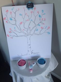 a white canvas with some paint on it and a tree painted on the side next to two cups