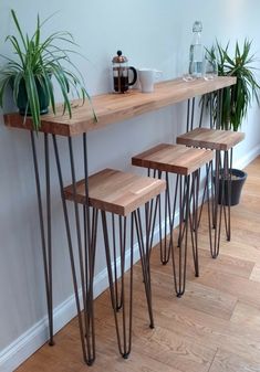 three wooden tables with hairpint legs and plants next to each other on a hard wood floor