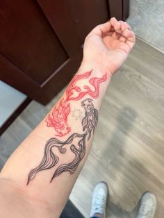 a woman's arm with a red and black dragon tattoo on the left wrist