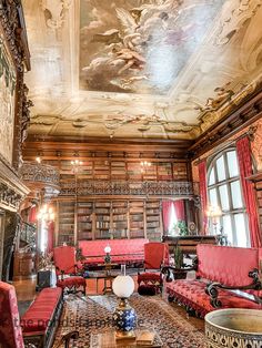 an ornately decorated living room with red couches and paintings on the ceiling above