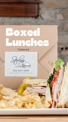 a lunch box with a sandwich and chips on the side that says boxed lunches