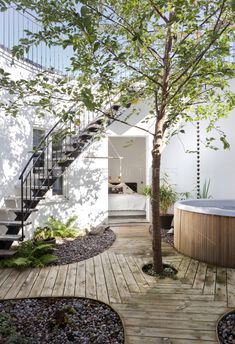 an outdoor hot tub in the middle of a wooden deck next to a tree and stairs