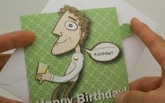 a person holding up a birthday card with a cartoon character on it and the words happy birthday