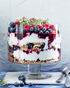 a cake with berries, blueberries and cream on top is sitting on a table