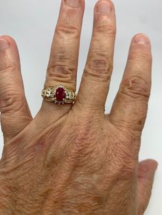 A simply stunning vintage natural ruby and diamond halo style ring. Whether worn as an alternative engagement ring, a July birthstone ring, anniversary surprise (it is the traditional gemstone for 40th anniversary), or just because this ring will not fail to impress. Crafted of 14k plumb gold which is guaranteed to test at exactly 14k or higher, it is stamped 14KP which denotes this fact. The central oval natural ruby is the star of the show, measuring 7 X 5 MM and weighing approximately 1 carat Red Ruby Ring Vintage, Ruby And Diamonds Ring, Antique Ruby Engagement Ring, Ruby And Diamond Ring Vintage, July Stone Ring, Gold Ring Ruby, Engagement Ring With Birthstones, Heirloom Ruby Ring With Emerald Cut Center Stone, Vintage Red Ruby Ring With Halo Setting