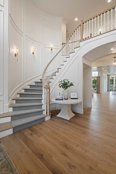 a white staircase in a large home with wood floors