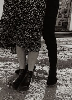 two people standing next to each other in front of a building with snow on the ground