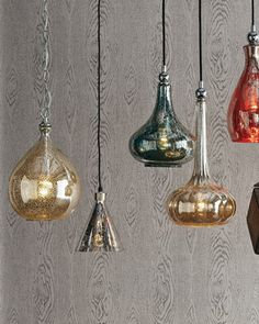 five different colored glass vases hanging from chains on a wall with letters below them