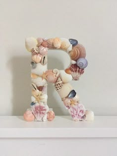 there is a letter made out of seashells on the shelf next to it