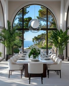 a dining room with an arched window overlooking the ocean and palm trees is pictured in this image