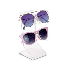 two pairs of sunglasses sitting on top of a clear display case with purple tinted lenses