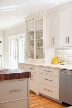 a kitchen with white cabinets and wood counter tops, along with a stainless steel dishwasher