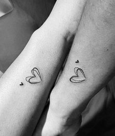 two people holding hands with tattoos on their arms, one has a heart and the other has