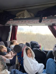 people sitting in the back of a van with blankets on their heads and hoods