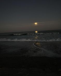 the moon is setting over the ocean with waves