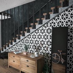 a wooden table sitting under a stair case next to a wall with geometric designs on it