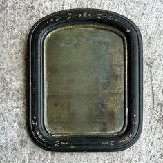 an old black framed mirror sitting on the ground