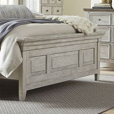 a white bed sitting on top of a wooden floor next to a dresser and mirror