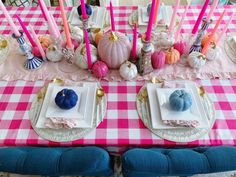 a pink and white checkered table cloth with place settings for two blue pumpkins