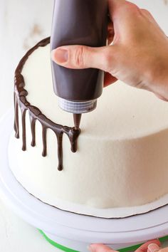 a person is decorating a cake with chocolate icing on the top and bottom