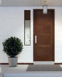 a white brick wall with a potted plant and mirror on the front door way