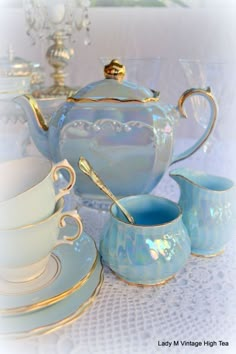 a blue tea set sitting on top of a table next to cups and saucers