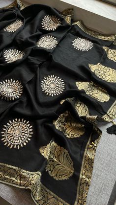 This elegant black saree is crafted from 100% pure Munga silk with intricate Banarasi weaving, featuring a stunning blend of gota patti, zardozi, and pearl work. The exquisite detailing with moti, zardozi, and cutdana adds a sophisticated touch, making it a perfect choice for formal events or festive occasions. Paired with a matching pure Munga silk blouse, this saree embodies timeless craftsmanship and luxury. Fabric of Saree: 100% Pure Munga Silk Banarasi Weaving Work: Gota Patti, Zardozi & Pe Black Embroidered Silk Saree, Black Silk Embroidered Saree, Bridesmaids Saree, Black Embroidered Saree Fabric, Black Saree With Golden Border, Black Silk Embroidered Saree Fabric, Lehenga Bridesmaid, Pearl Work, Bridesmaid Saree