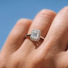 a woman's hand holding an engagement ring with a large emerald stone in it