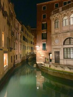 an empty canal in the middle of a city at night with buildings on both sides