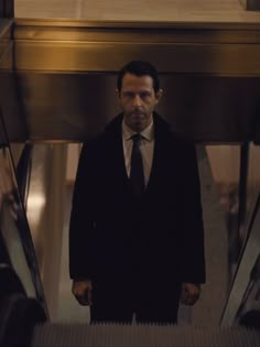 a man in a suit and tie standing on an escalator