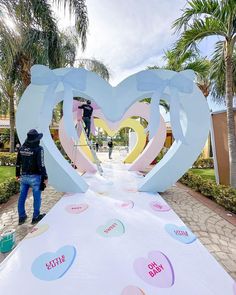 a man standing next to a giant heart cut out of paper on top of a walkway