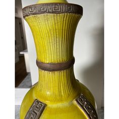 a yellow vase sitting on top of a table