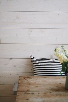 a vase with white flowers sitting on a wooden table next to a black and white pillow