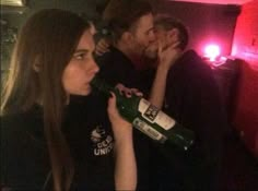 two people are kissing while drinking from a bottle